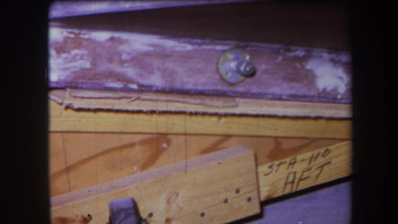 1964 8mm close-up from Yucaipa-area footage showing varnished wooden pieces, a round metal screw head, nails, and handwritten STA-110 AFT-style notation.