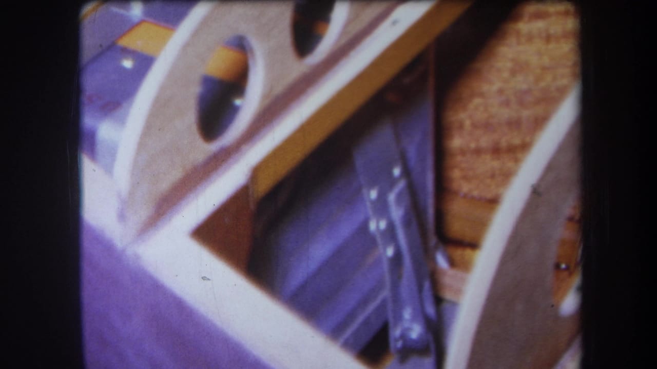1964 Yucaipa 8mm close-up of a pale wooden object with circular cutouts, purple material, and a yellow-orange strip.