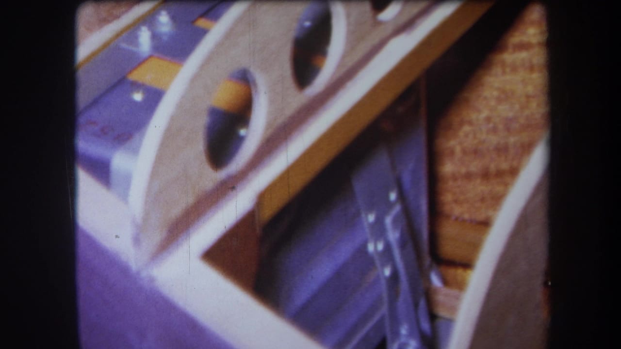 1964 Yucaipa home-movie frame showing an angled detail of wood, purple-painted metal, circular cutouts, and reflective fixture parts.