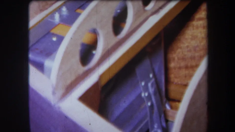 1964 Yucaipa 8mm frame with soft focus on pale wood, purple-painted metal, rounded openings, and small reflective hardware.