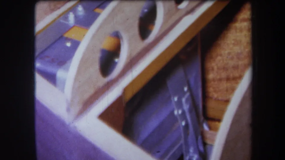Final 1964 Yucaipa frame showing wood, purple-painted metal, circular openings, yellow panels, and tan textured material.
