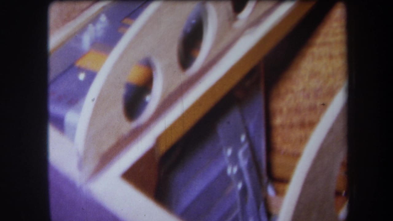 Close-up of purple-painted and wooden boat parts with circular openings and dark film borders.
