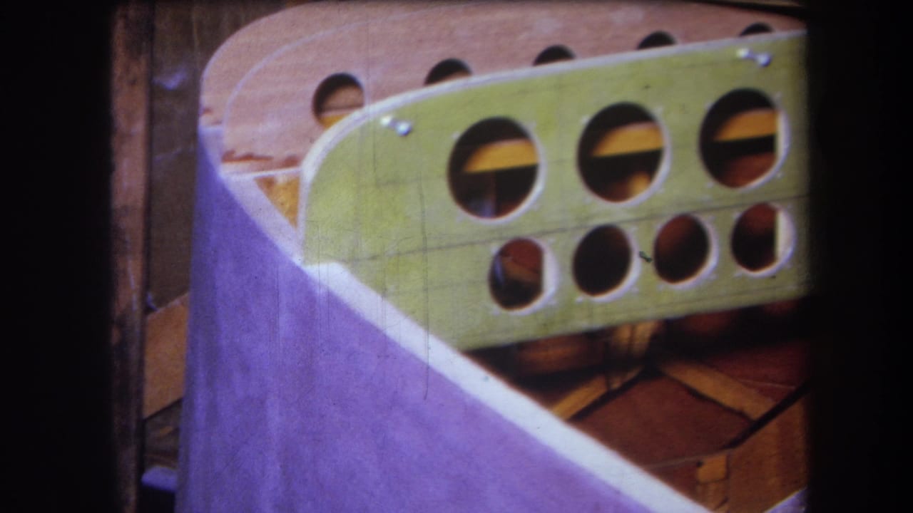 1964 Yucaipa-area 8mm frame showing a green painted wooden panel with circular openings, screws, and tan internal framing.