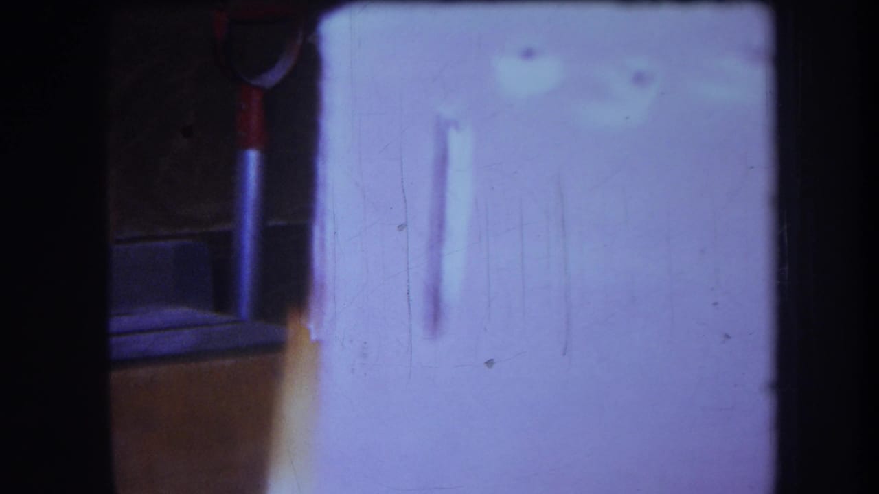 1964 Yucaipa-area 8mm frame showing a white cupboard door with small circular holes and a dark surrounding interior edge.