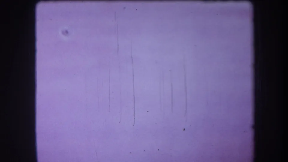 Final 1964 8mm frame holds on the pale cupboard door, showing faint marks, small specks, and aged purple film color.