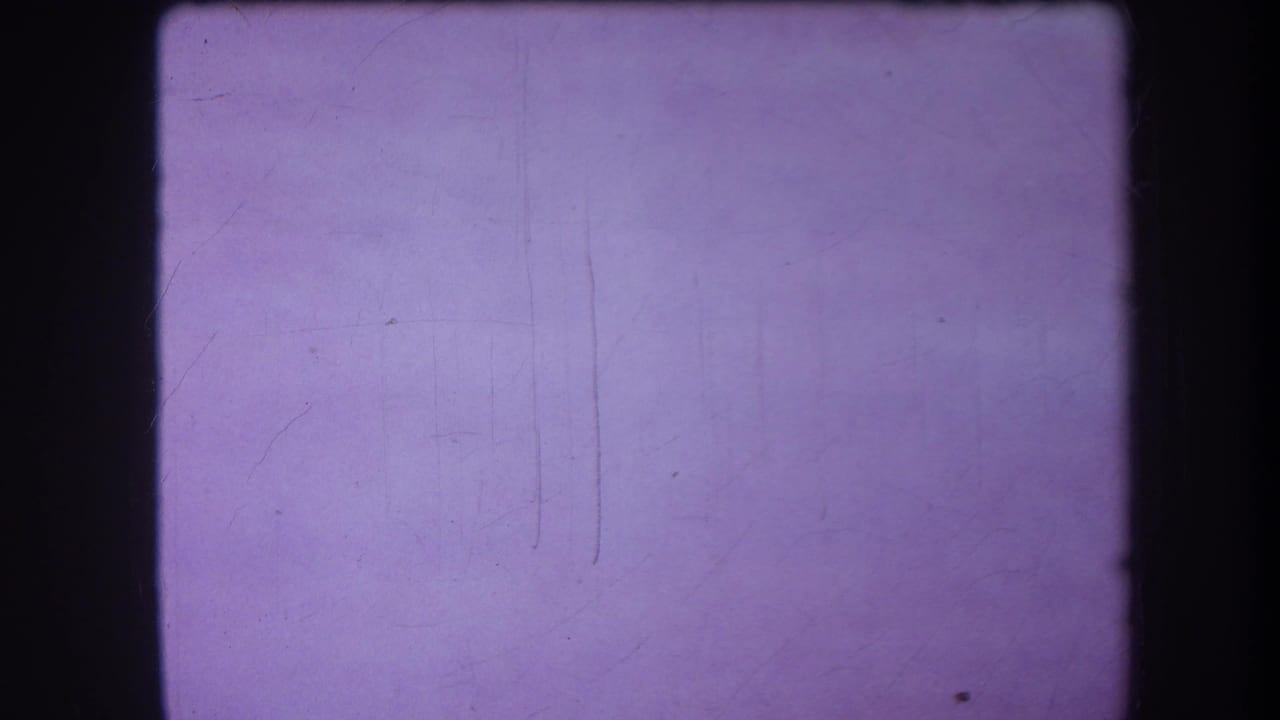 Blank purple 8mm frame from the supplied 1964 Yucaipa reel, showing soft grain, dust, and vertical scratch marks.