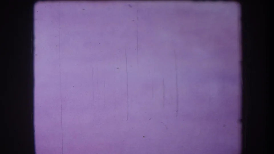 Purple-tinted blank 8mm frame with visible film grain, small dust marks, and faint vertical scratches.