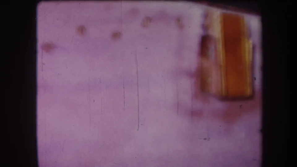 Final 1964 Yucaipa frame holds on the soft yellow shed-like structure at right, surrounded by purple color cast, film grain, and visible wear.