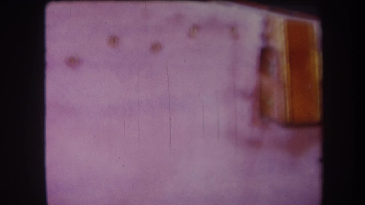 1964 8mm home-movie frame from Yucaipa showing a soft-focus close-up of a pale surface and tan wooden edge.