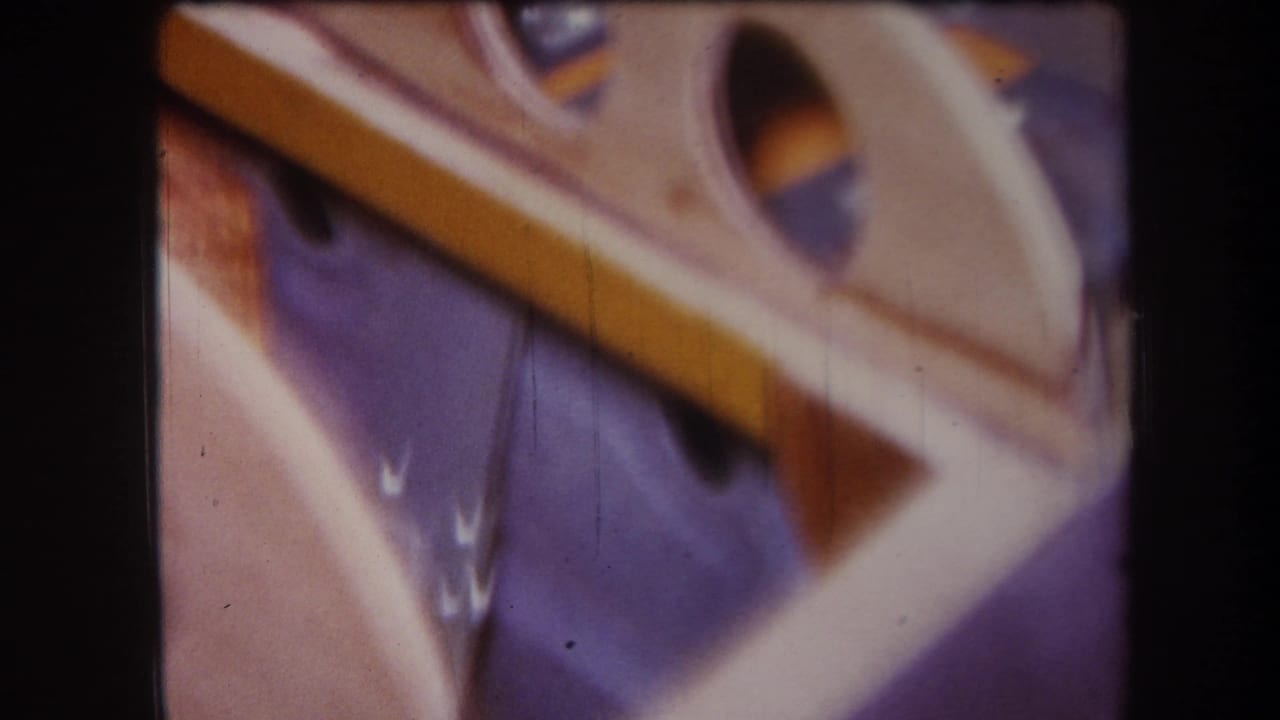 1964 Yucaipa 8mm frame showing a tan wooden frame with circular openings on a blue fabric-like surface.