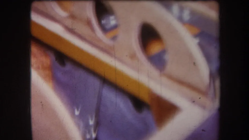 1964 Yucaipa 8mm still of a tan wooden object frame resting on blue fabric or a blue surface.