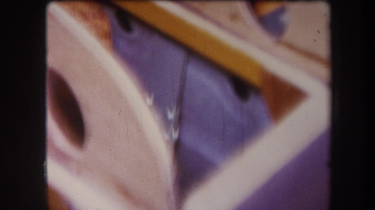 1964 8mm close-up from Yucaipa showing blurred angled wood pieces, rounded cutouts, and warm faded film color.
