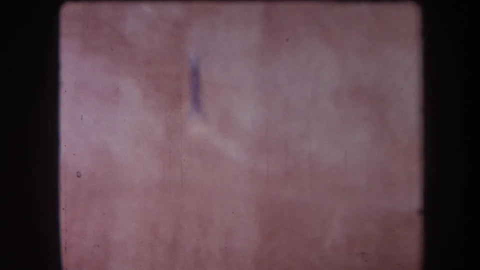 1964 Yucaipa frame with the camera drifting across a blurred work surface and a small blue mark or object near center.