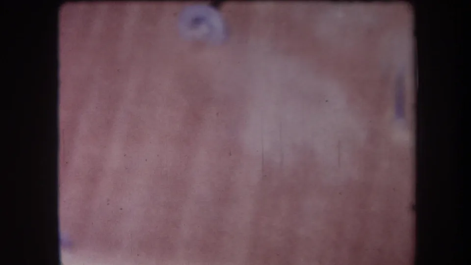 1964 Yucaipa-area 8mm frame showing a soft-focus wood surface with grain, dust marks, and dark film borders.