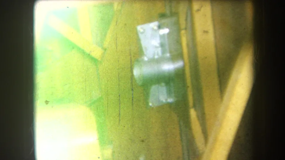 Soft exposed 8mm view of metal hardware fixed to a wooden structure, with color shift and visible film wear.
