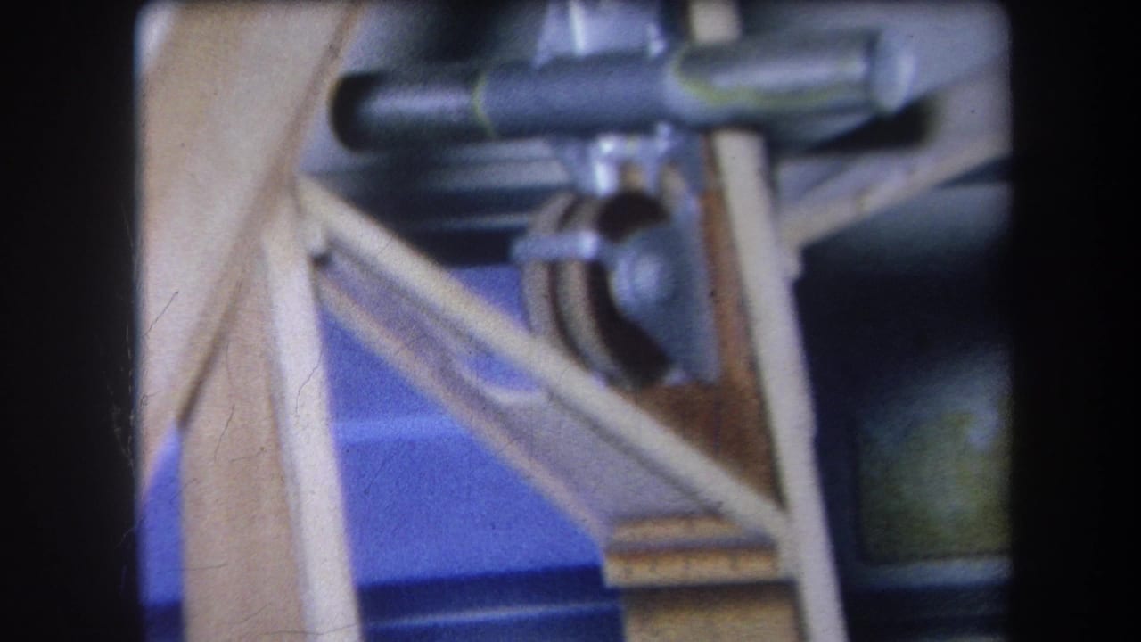 Close-up of wooden supports, blue backing, and metal pulley components.