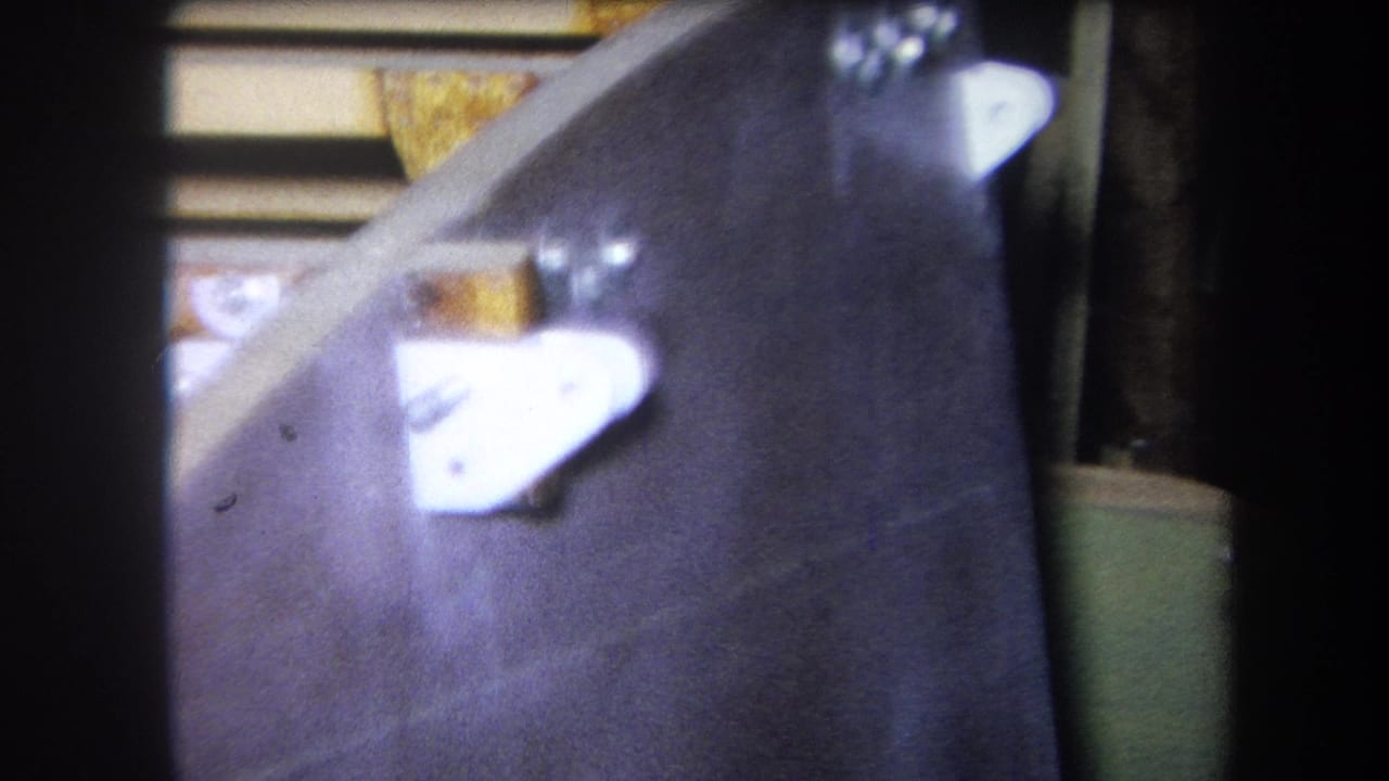 Close view of a dark object beside a greenish panel with analog gauges partly visible.
