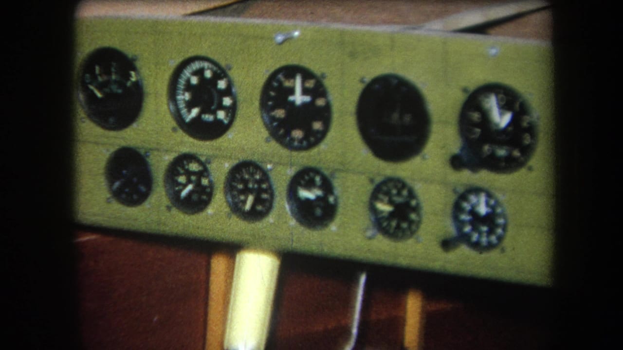 Close-up of a greenish-yellow analog control panel with rows of black circular meters in the 1964 Yucaipa home-movie footage.