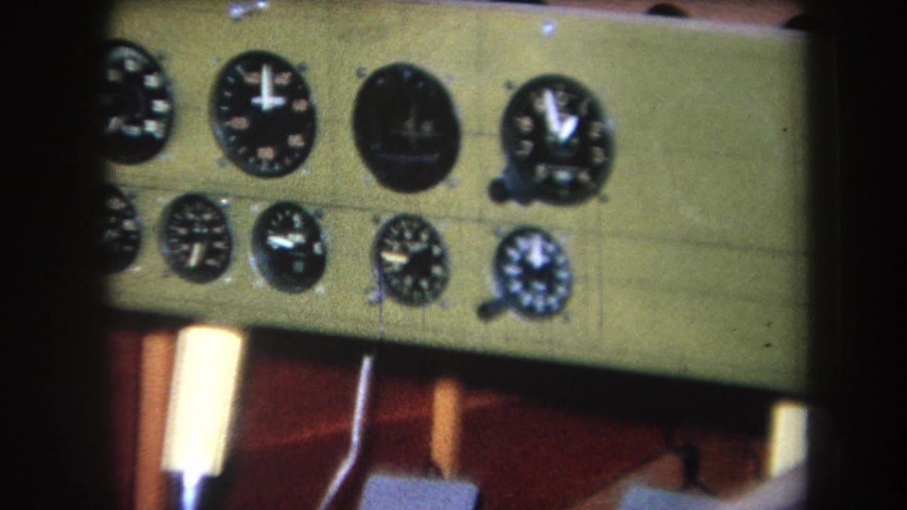 1964 8mm frame from Yucaipa-area footage showing analog gauges on a green panel set into a wooden dashboard.