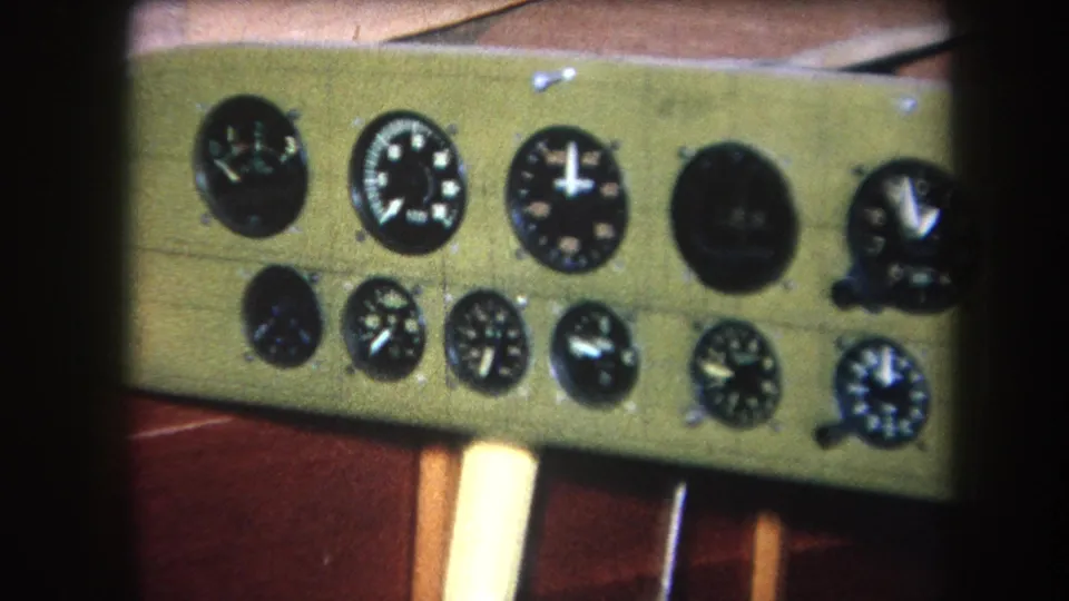Soft 8mm frame showing a shifted close view of analog gauges on a green panel, with wood trim below.