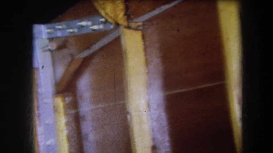 1964 Yucaipa frame showing a close, partly cropped view of the table underside with metal hardware, a pale support, and warm brown wood.