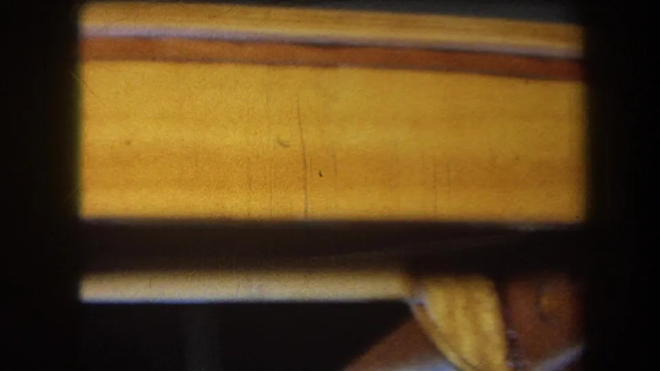 Final 1964 Yucaipa frame showing a horizontal varnished wood rail in close-up, with dark frame borders and warm brown tile beneath.