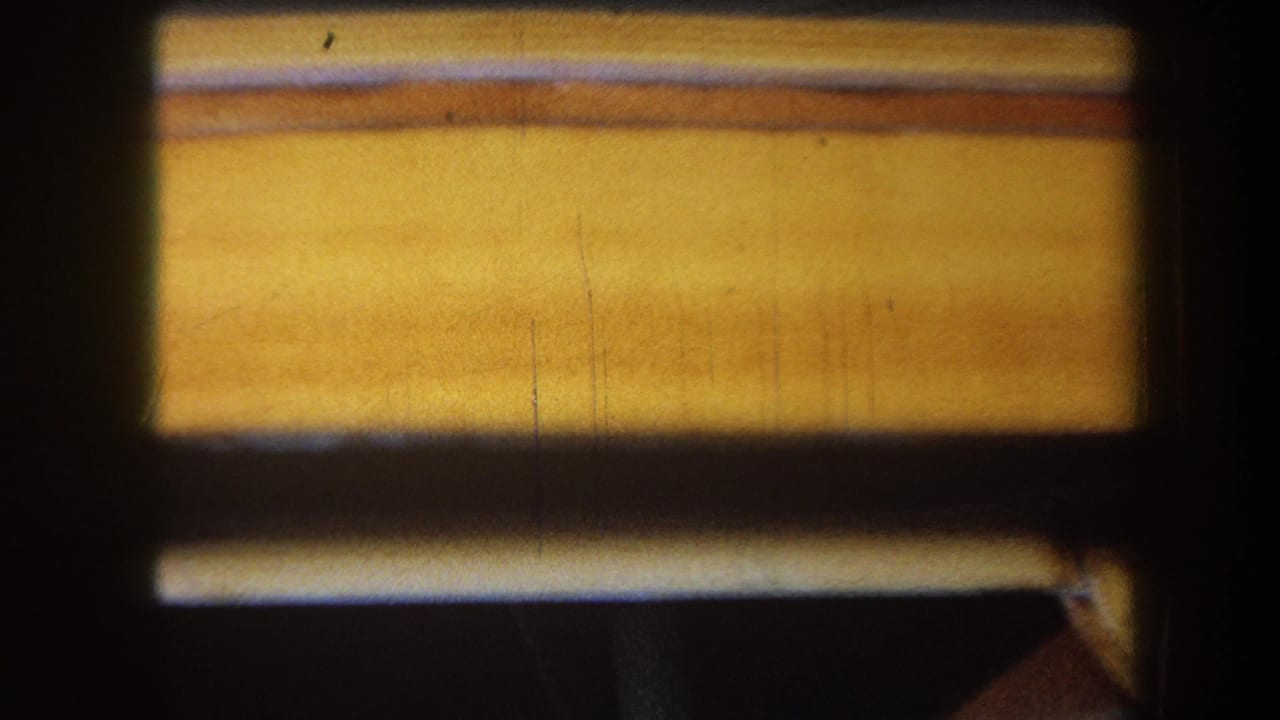 1964 Yucaipa home-movie frame showing a close, soft-focus view of varnished wood grain and a dark rectangular opening.