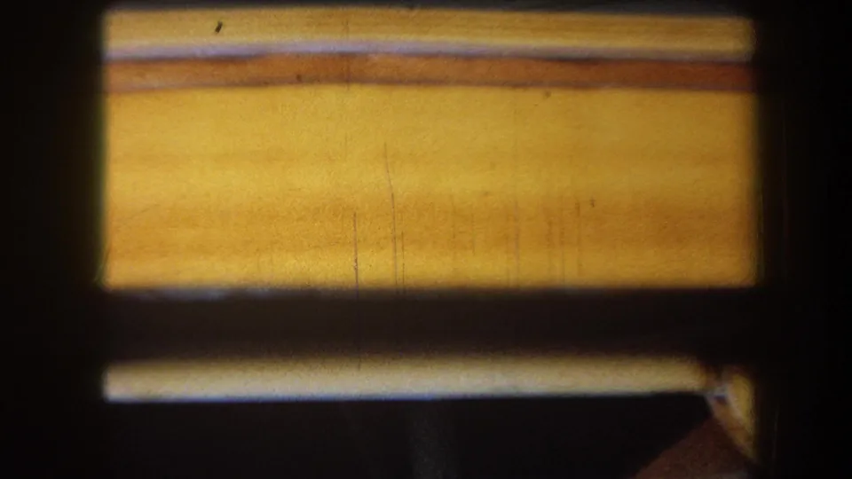 1964 Yucaipa home-movie frame showing a close, soft-focus view of varnished wood grain and a dark rectangular opening.