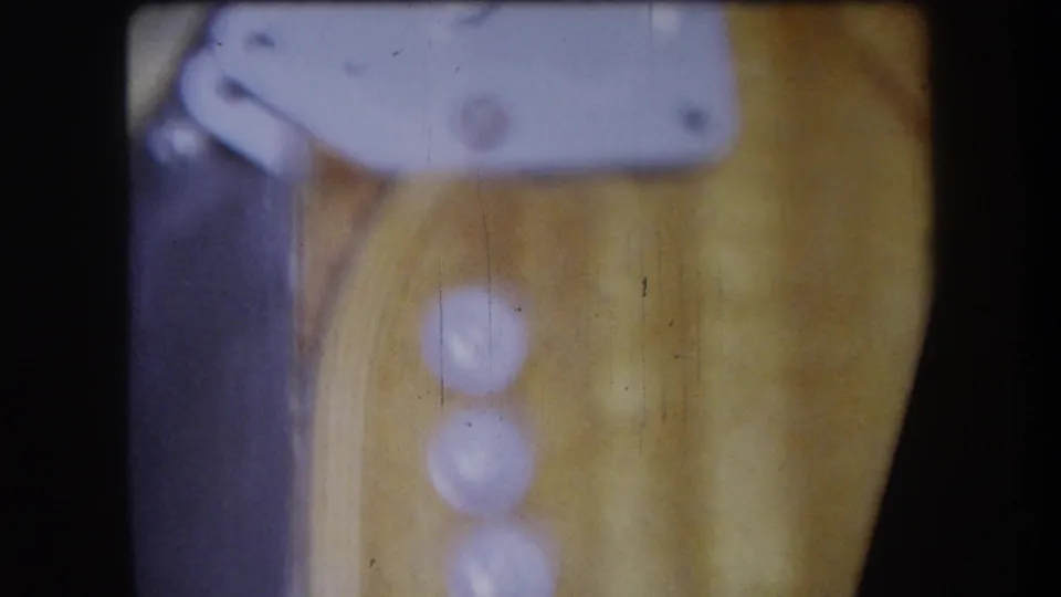 Close 1964 Yucaipa home-movie frame of three white dials on varnished wood beneath a pale metal mounting bracket.