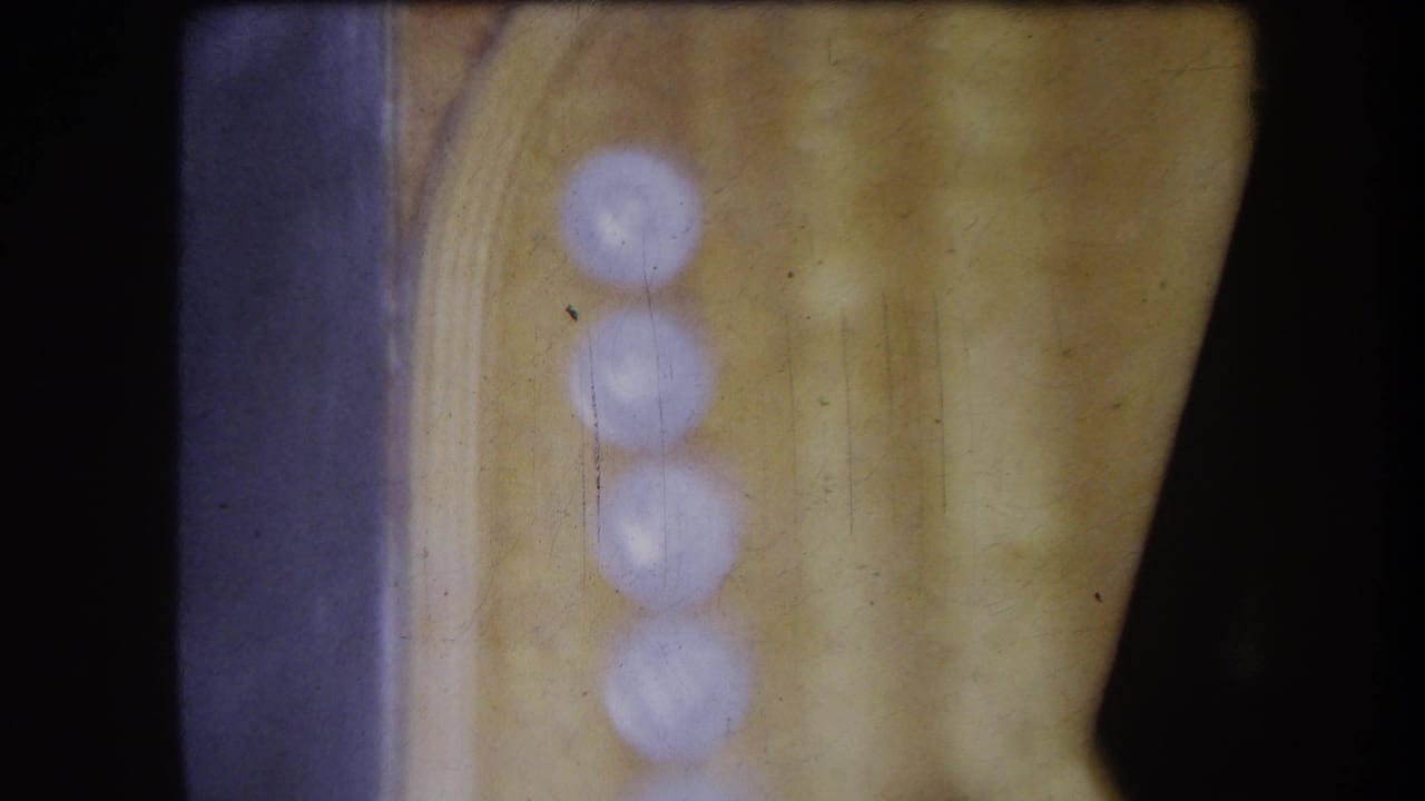 1964 8mm frame from Volmer Yucaipa showing a soft, close interior view of a panel edge and blurred circular highlights.