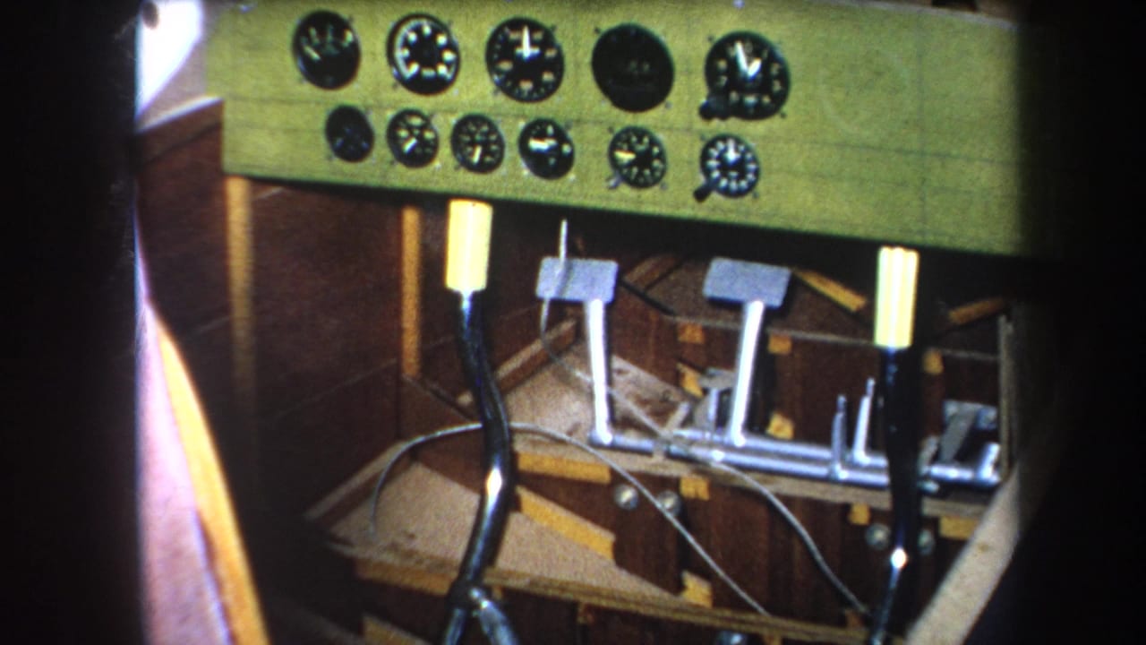 1964 8mm footage from Yucaipa, California, showing a close-up of an aircraft cockpit panel with analog gauges, pedals, joystick, and wooden interior structure.