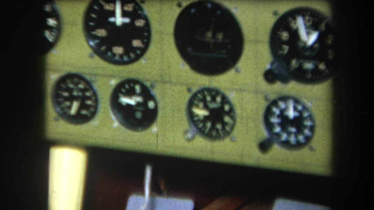 Aircraft cockpit panel with clustered black gauges and dark vertical framing.