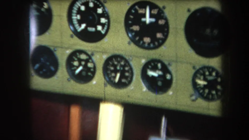 1964 8mm frame showing a tilted close view of analog aircraft instruments, with grain and motion softness from the scan.