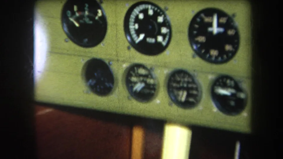 1964 home-movie frame from California metadata showing analog cockpit gauges on a pale panel, partially obscured by shadowed edges.