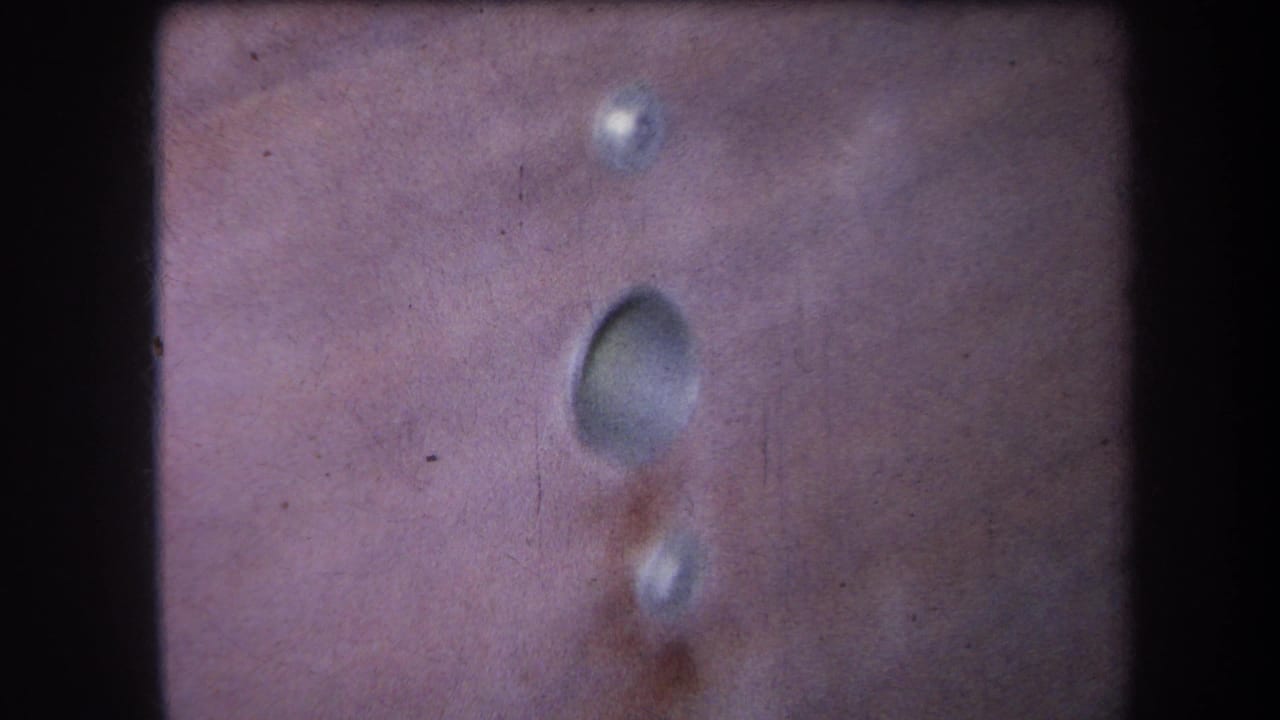 Similar close-up of a wooden panel with a central hole and small holes above and below.