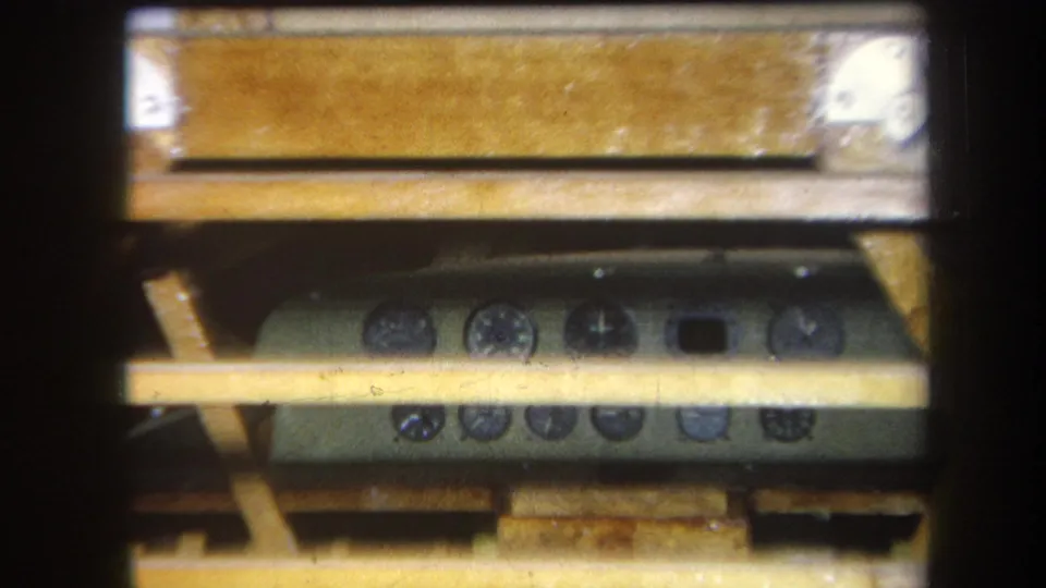 Close 8mm frame of a green-gray control panel under a wooden table in the 1964 Yucaipa footage.