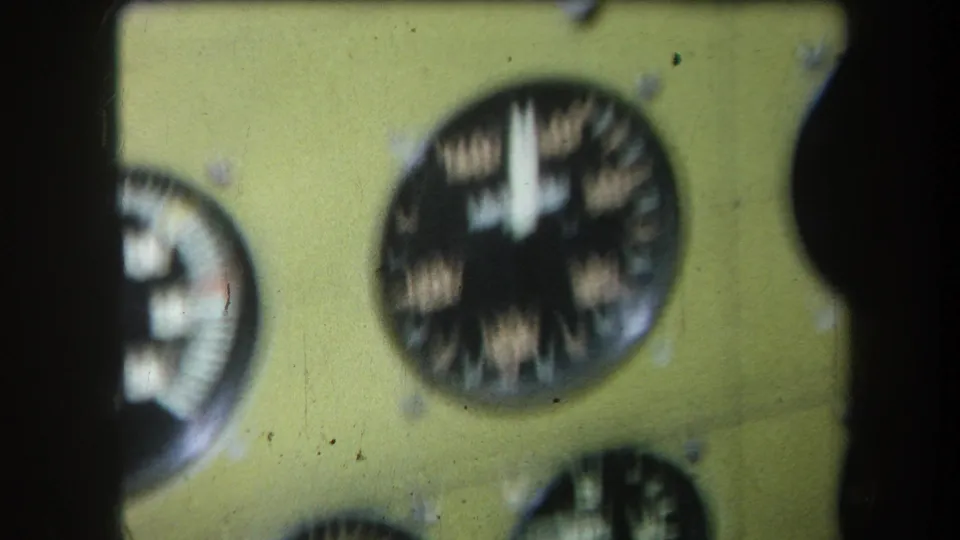Soft-focus 8mm close-up of a yellow instrument panel with multiple round gauges, likely part of mechanical equipment.