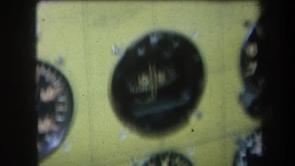 1964 8mm frame showing a yellow panel with a central dark analog dial and partial gauges at the sides.