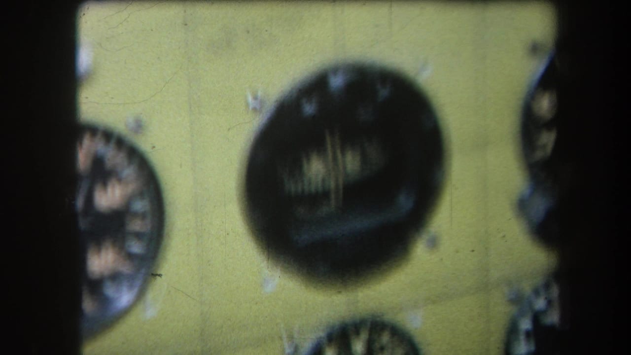 1964 8mm frame from Yucaipa showing a soft-focus yellow instrument panel with round analogue dials and white markings.