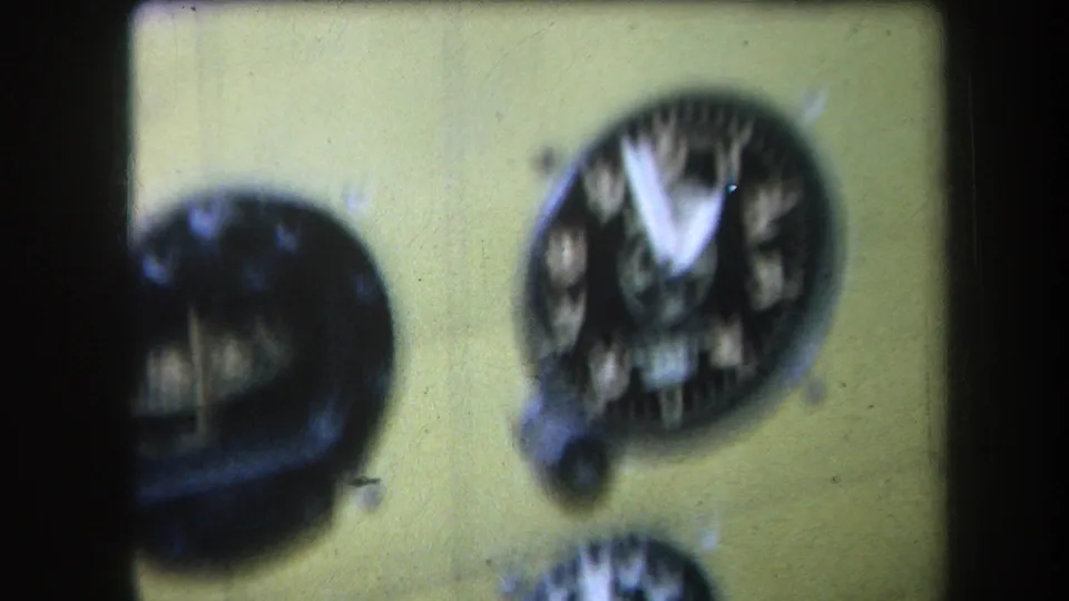 1964 Volmer Yucaipa home-movie frame of a yellow airplane cockpit panel, with blurred circular gauges and visible film borders.