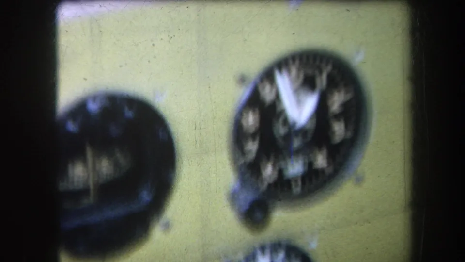 1964 Volmer Yucaipa frame showing a handheld 8mm close-up of a yellow aircraft instrument panel with round analog dials.