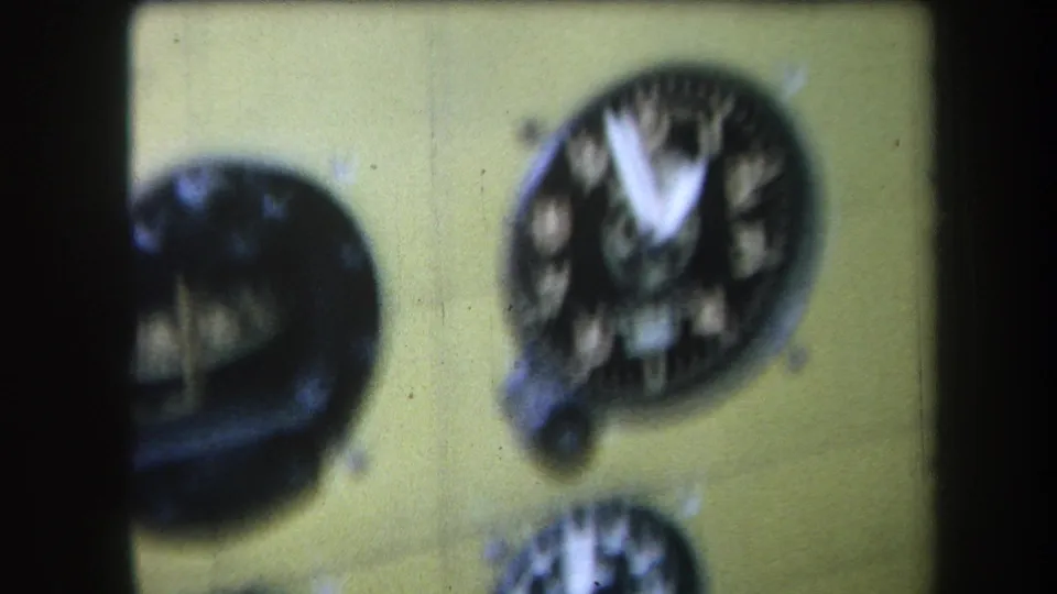 1964 Volmer Yucaipa footage frame of a yellow airplane cockpit instrument cluster, with analog gauges softened by home-movie focus.