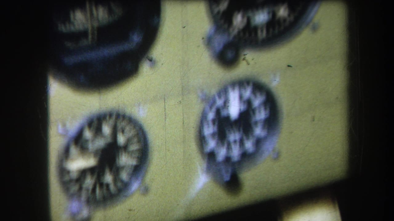 1964 8mm frame showing a soft-focus aircraft instrument panel with clustered analog dials and visible film texture.