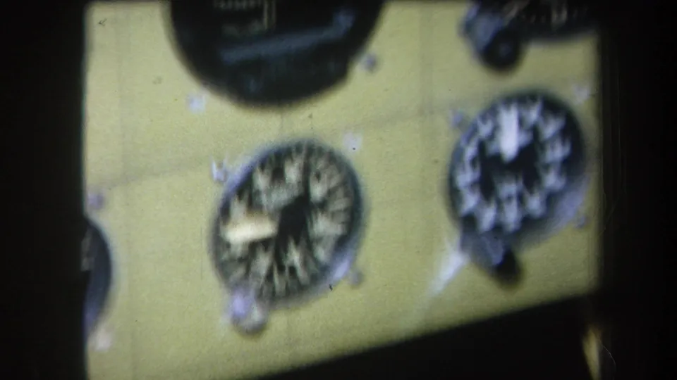 1964 8mm frame with a close, blurred view of analog aircraft instruments on a yellow-green panel in home-movie footage.
