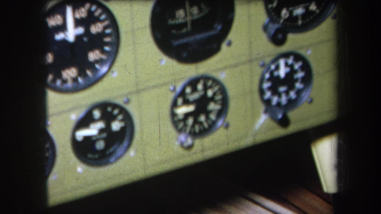 Close view of round aircraft gauges on a pale green cockpit panel.
