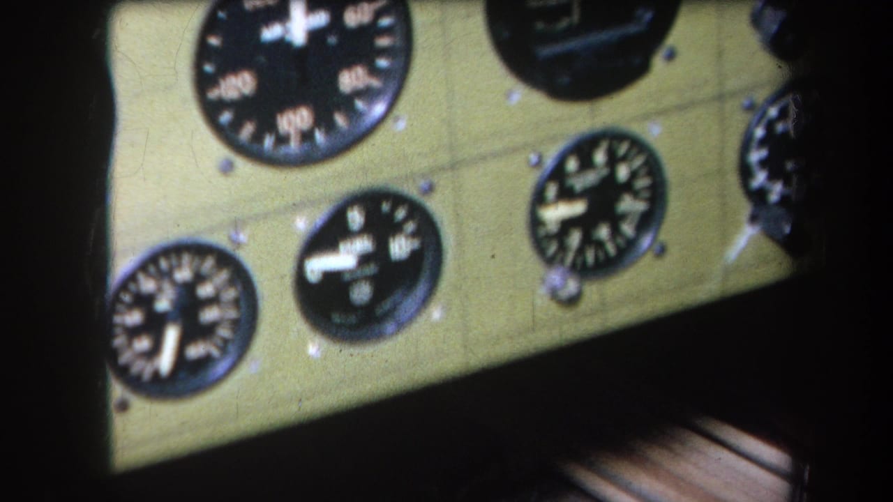 Close 1964 home-movie view of black-faced aircraft instruments set into a pale green cockpit panel.