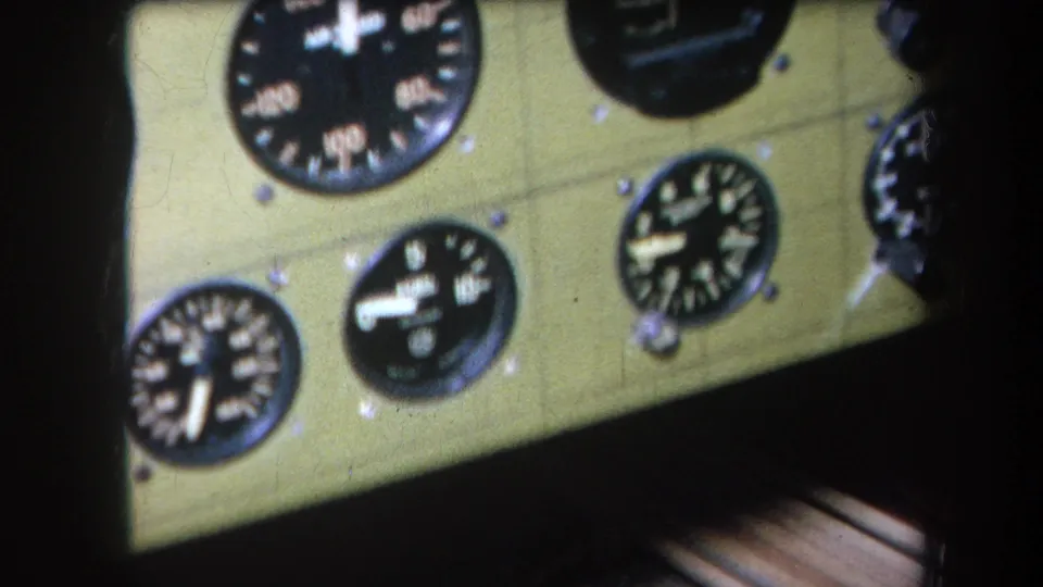 Close 1964 home-movie view of black-faced aircraft instruments set into a pale green cockpit panel.