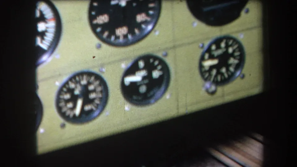 Handheld 8mm frame showing a tilted view of vintage aircraft gauges in the cockpit panel.