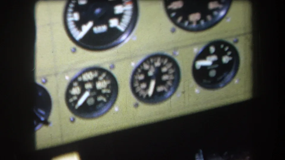 1964 home-movie frame with several cropped round aircraft gauges set into a green-painted cockpit panel.