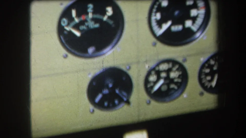 Final 1964 8mm view of the same analog gauge panel, with black dials, white markings, and a dark shadow at the side.
